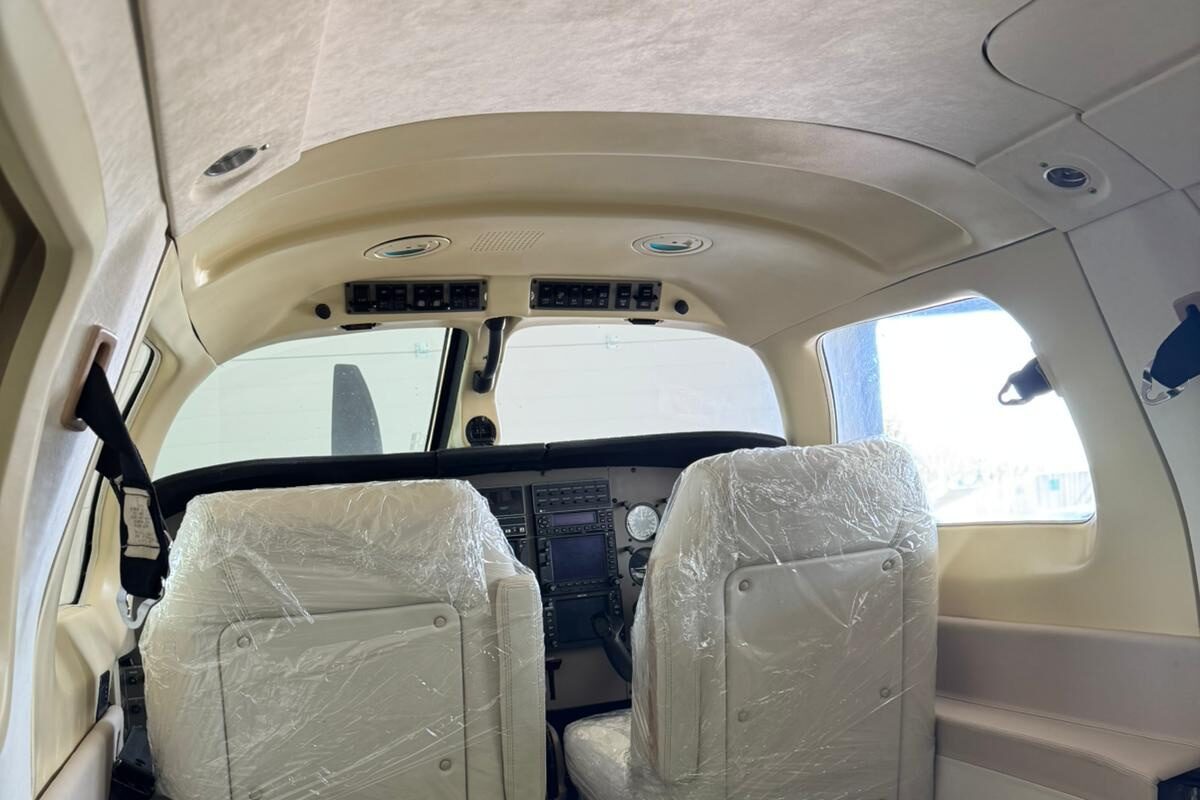 New seats refitted in the cabin, still shrink-wrapped, looking forward past the seat backs to the flight deck; floor and sill protected with covers during install.