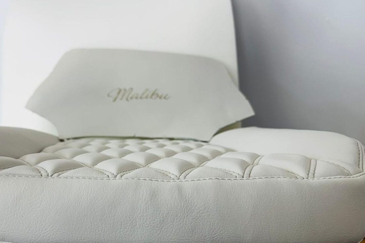 New seat base and headrest in white leather on the trim bench, button-tufted squab, Malibu script embroidered into the headrest face.