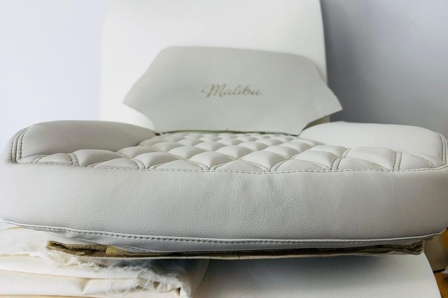 New seat base and headrest in white leather on the trim bench: button-tufted squab, Malibu script embroidered into the headrest face.